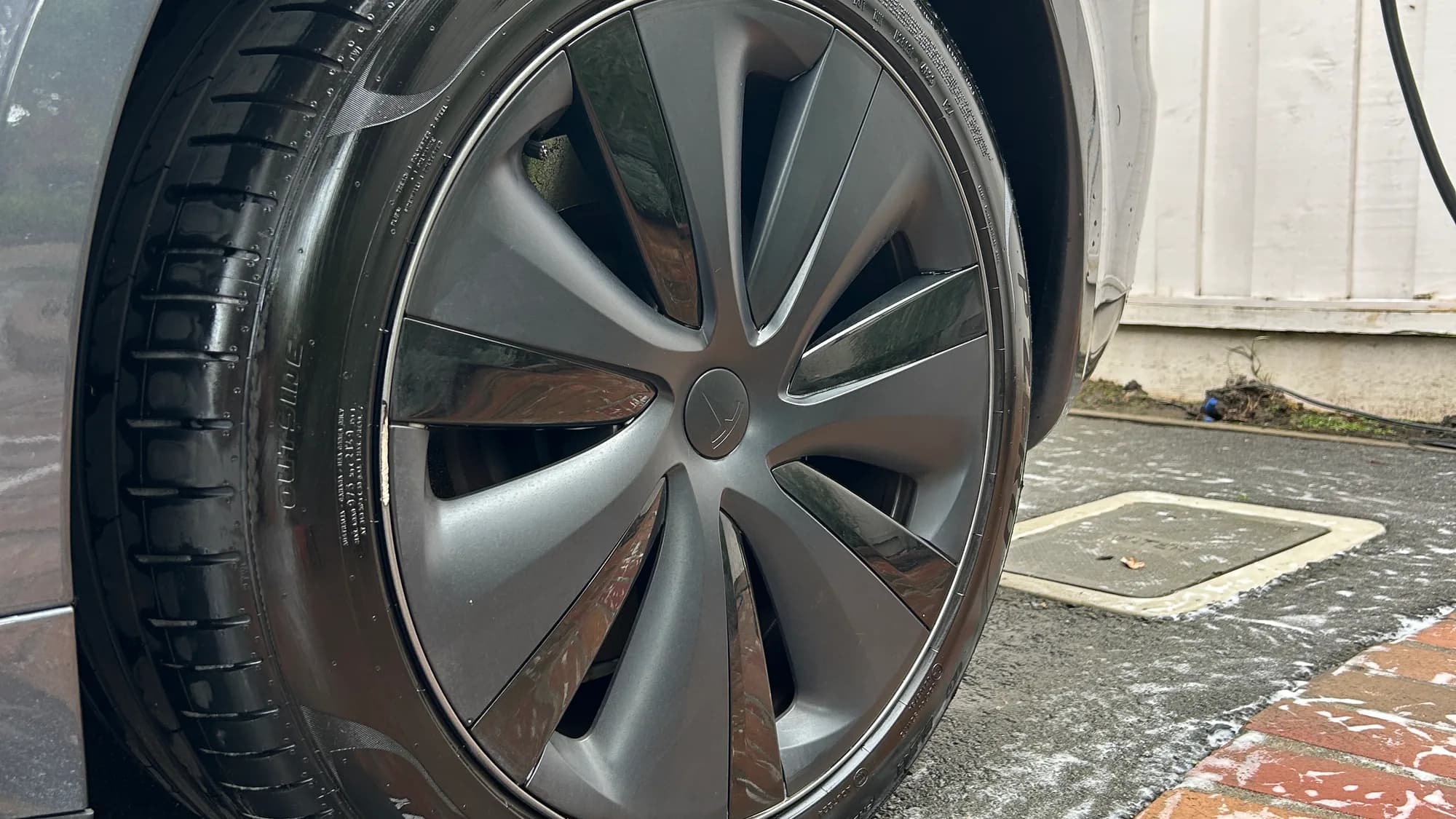 The same Tesla Model S wheel after a Full Detail, with the wheel face cleaned and the tire dressed black