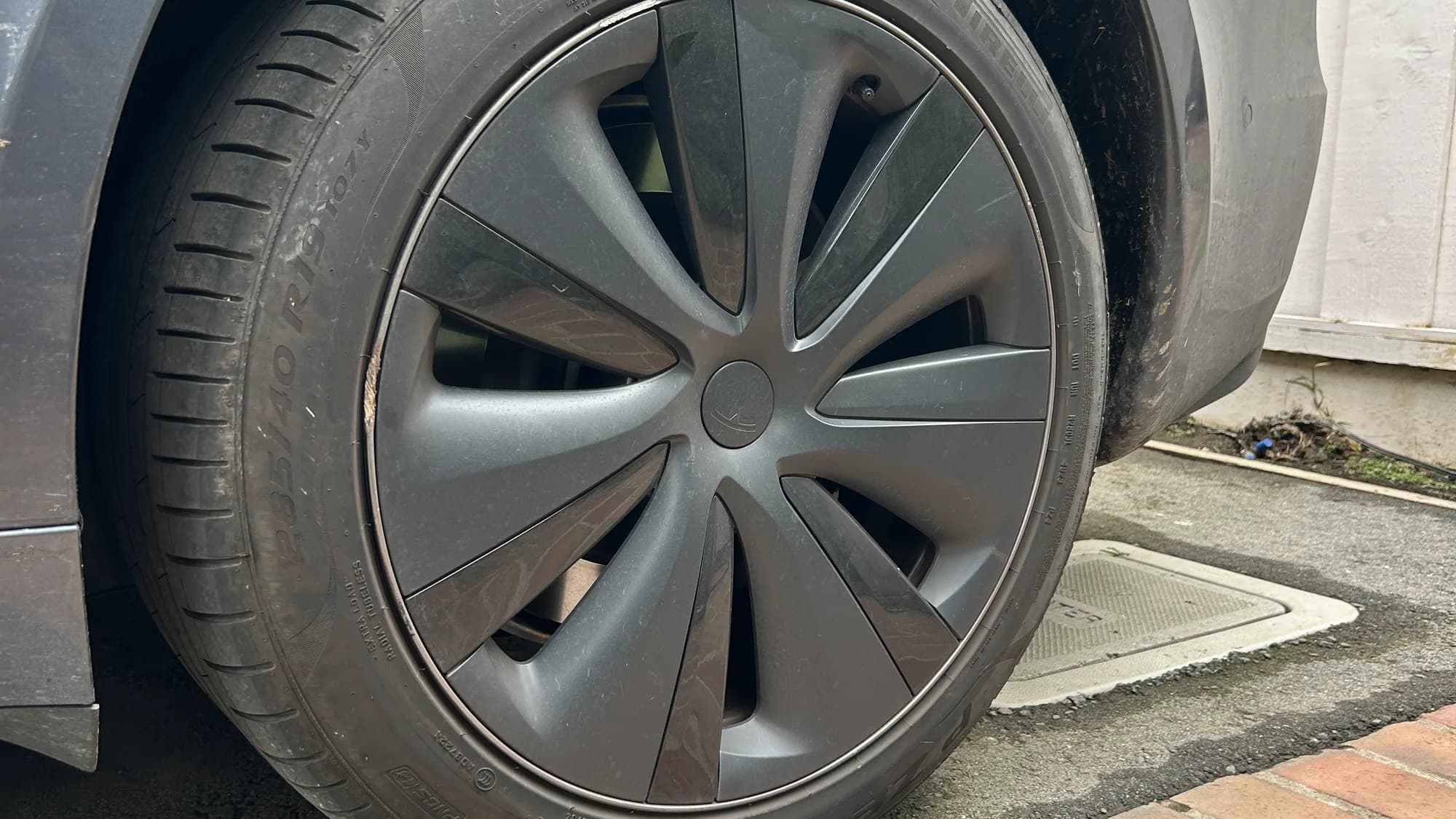 Tesla Model S wheel before a Full Detail, with a dull, soiled tire sidewall and grime in the wheel arch